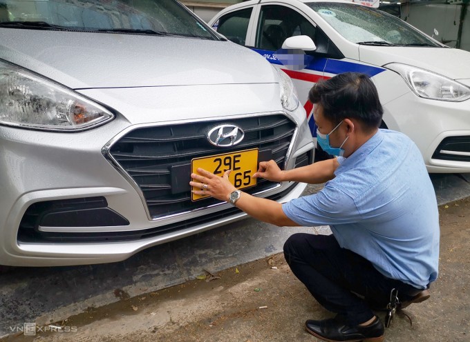 Tài xế xe taxi ở Hà Nội gắn biển màu vàng lên xe.