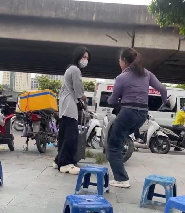 Hình ảnh chị K đá vào va li của cô gái đứng trên vỉa hè